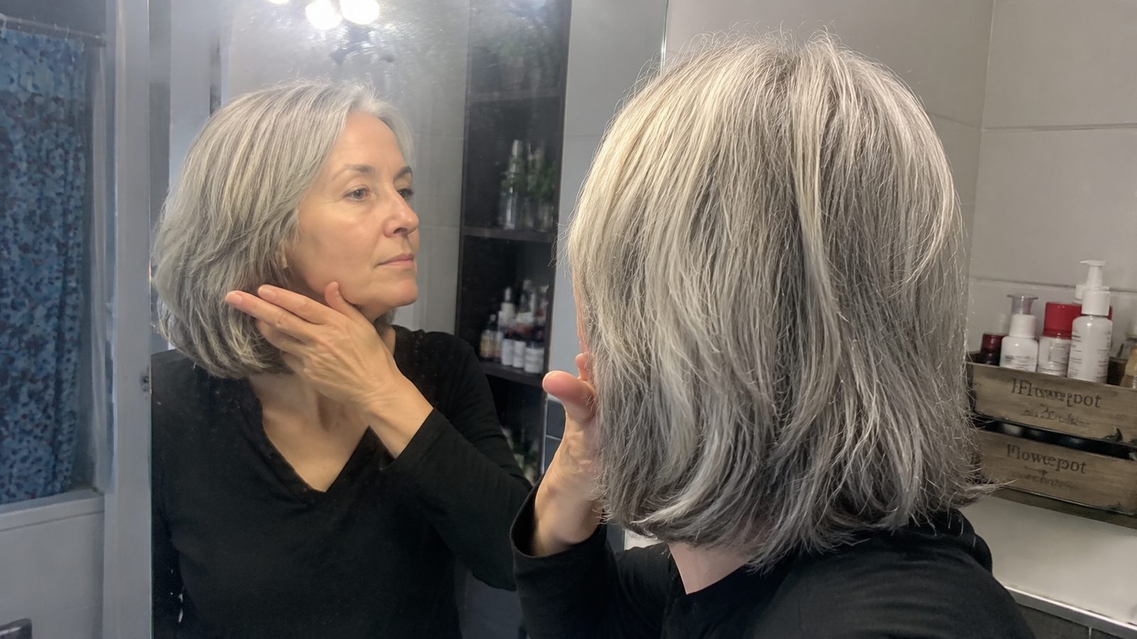A woman holding two fingers under her jaw at the mirror, running the mirror test