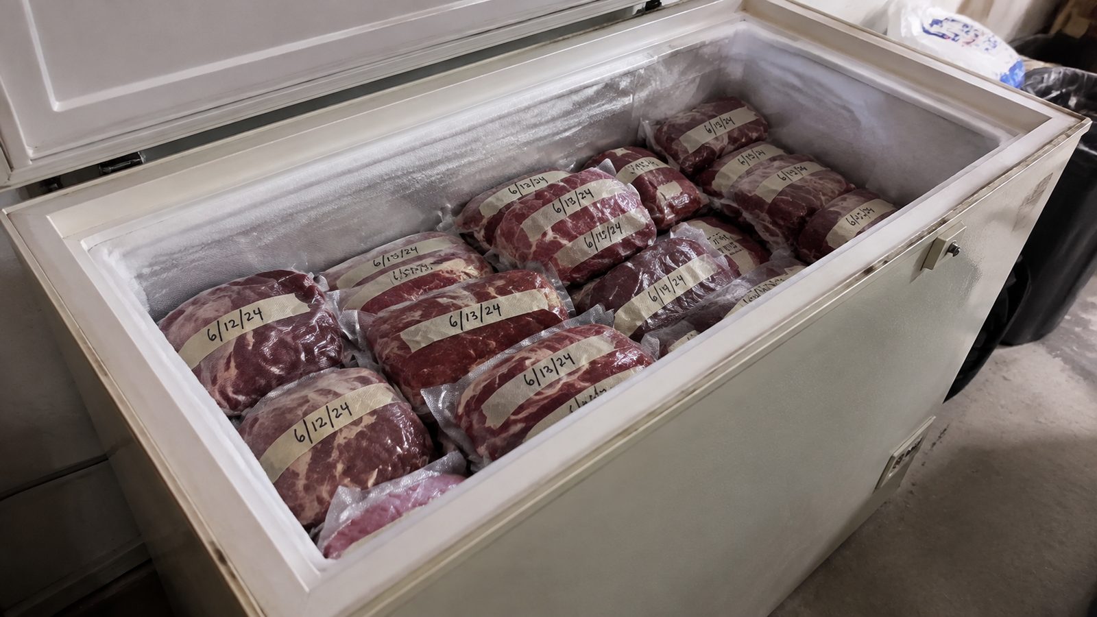 An open chest freezer packed with sealed, dated portions of beef.