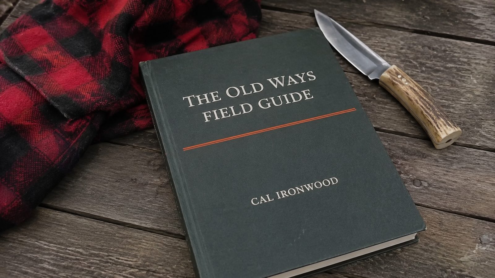 The Old Ways Field Guide, printed and laid open on a plank table with a knife and a coil of cordage